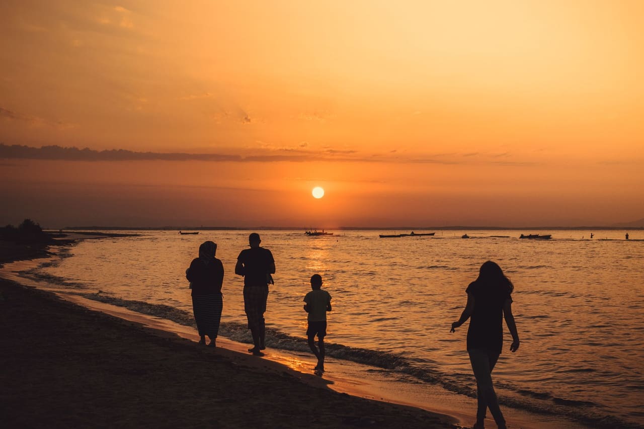 A family walking together along the shoreline at sunset